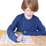 boy tracing letters on a wipe clean sheet