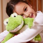 girl holding weighted stuffed animal frog