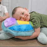 boy hugging the weighted tickley tactile turtle